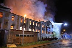 Sachsen / Rabenau: Am 14.05.2026 kam es gegen 20.50 Uhr in Oelsa zu einem Großbrand. An der Hauptstraße brannte ein ehemaliges Gebäude einer Polstermöbelfabrik. Aktuell soll das Gebäude fast leer gestanden haben. Einzig ein oder zwei Firmen sollen derzeit Mieter gewesen sein. Als die Feuerwehr eintraf, stand der Dachstuhl lichterloh in Flammen. Das Feuer breitete sich schnell auf das gesamte Gebäude aus. Die Rauchwolke war kilometerweit zu sehen. Schnell mußten weitere Kräfte nachalarmiert werden. Am Ende waren über 130 Feuerwehrleute der Freiwilligen Feuerwehren Rabenau, Freital, Bannewitz, Dippoldiswalde, Kreischa und Pirna im Einsatz. Zunächst gelang es, die umliegenden Häuser zu schützen. Mit mehreren Strahlrohren gelang es den Brand unter Kontrolle zu bringen. Erst nach mehreren Stunden konnte das Feuer gelöscht werden. Das DRK versorgte die Einsatzkräfte mit Essen und Getränken im nahen Gerätehaus der Freiwilligen Feuerwehr Rabenau. Die Hauptstraße in Oelsa war wegen des Einsatzes gesperrt. Die Polizei ermittelt zur Brandursache.